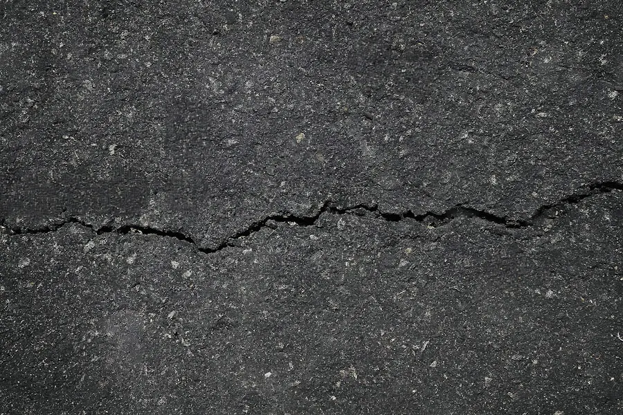 Single crack running across weathered asphalt